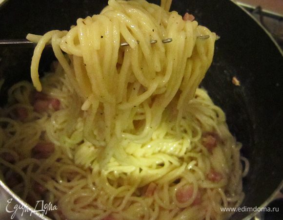 Затем частями добавляем спагетти к соусу, непрерывно и быстро перемешивая. Яичная смесь должна окутать пасту со всех сторон, но не стать омлетом и не пойти хлопьями. 