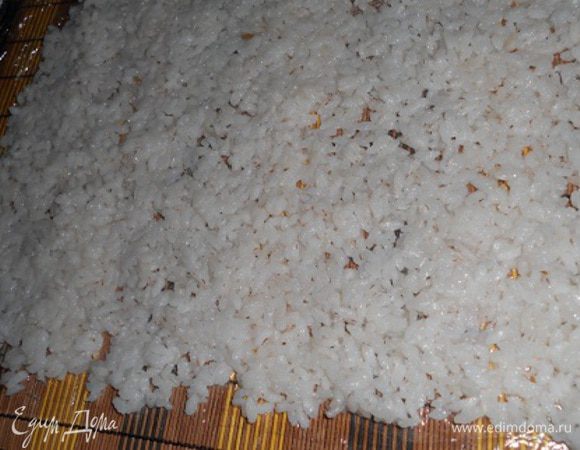 Крабовые палочки или крабовое мясо нарезать на кусочки. Вареные яйца порезать кубиками.Добавить кукурузу и майонез и перемешать.Теперь взять коврик для суши или фольгу,сверху покрыть пищевой пленкой и выложить слой риса - тонкий.  