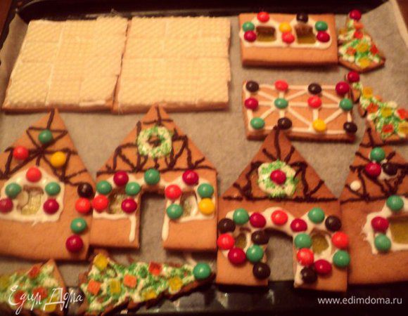 Выложить глазурь в целлофановый пакетик, отрезать кончик уголка.  Разрисовать с помощью этого корнетика детали домиков, елочки, украсить конфетками, кокосовой стружкой, растопленным шоколадом, деталями из вафельных коржей выложить крышу. Стекла окон сделать из пластинок мармелада, прикрепив их глазурью. Оставить детали сушиться на ночь.