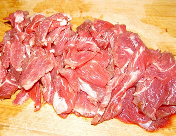 Подмороженное мясо говядины нарежьте очень тонкими полупрозрачными ломтиками.