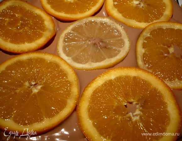 Собираем торт. На решетку, поставленную на блюдо (так чтобы могла стекать глазурь) ставим дно разъемной формы кладем ванильный корж, обильно поливаем его сиропом киви или апельсиново-лимонным, выкладываем крем, затем ломтики апельсинов и лимона.