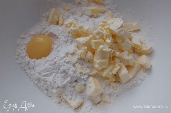 Муку просеять в миску. Добавить масло, нарезанное кусочками, желток и соль.