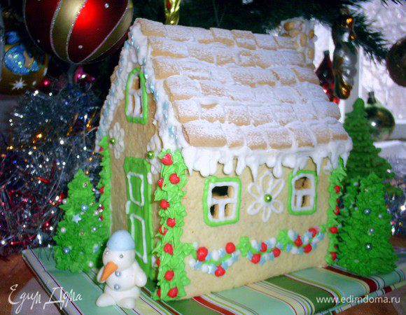 Когда домик хорошо просохнет, начинаем его украшать. Рисуем окна, ставни, гирлянды, расписываем стены - все что вашей душе угодно и на что хватает фантазии и инструментов. Поверхность крыши равномерно обмажьте глазурью, я делала это с помощью чайной ложечки, и выложите печенье-подушечки. У меня было печенье - бамбук, нарезанное на кусочки. Глазурь должна быть очень густой, чтоб черепица на сползала. Можно добавить в айсинг немного пудры, если потребуется. Из ситечка посыпаем крышу пудрой, имитируя снежок. Неровные края крыши и все огрехи маскируем глазурью. По краю крыши делаем сосульки. Прикасаемся кулечком к краю крыши и несильно нажимаем, глазурь стечет, образуя сосульку. Регулировать длину и толщину сосулек можно силой нажатия на кулек.
