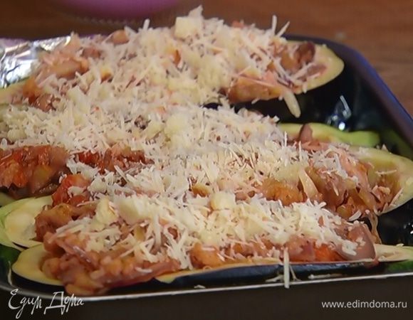 Небольшой глубокий противень выстелить фольгой, плотно выложить лодочки из баклажанов и наполнить их овощной начинкой.