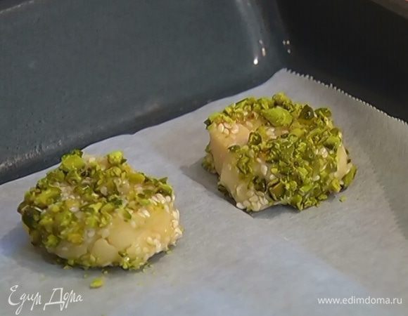 Каждый кружок теста обмакнуть с двух сторон сначала в кунжутную карамель, затем в фисташки и выложить на противень.