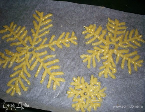 Полученным тесто наполняем кондитерский мешок, кулечек, пакет, файл - то, что у вас есть под руками. Срезаем уголок, чтоб получить диаметр отверстия примерно 5 мм. Определяемся  с размерами нашей будущей елки. Нужно выбрать диаметр нижнего яруса и разницу между ярусами. У меня диаметр нижнего яруса был 16 см, а разница - 1 см.
Теперь на пергаменте с помощью циркуля чертим круги-шаблоны, уменьшая радиус каждого следующего на 0,5 см. Вы можете сделать свою елочку больше или меньше. Смотрите сами по желанию.
Теперь рисуем еловые лапы. В центре каждого круга рисуем маленький круг, затем 6 лучей и на каждом - веточки-иголочки. По своему опыту советую рисовать их более густо, чем у меня на фото, чтоб детали были прочнее. Теста получается достаточно и я сделала пару запасных ярусов, которые впоследствии мне очень пригодились. Если тесто осталось, выдавите из него произвольные фигурки - ваши домочадцы будут вам очень благодарны.