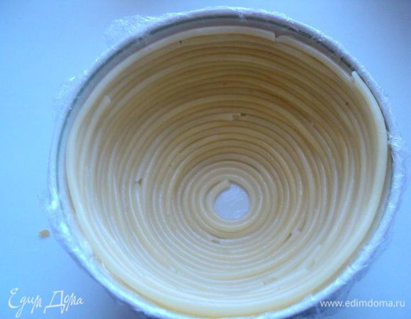 Салатник в виде полусферы (у меня 2 штуки Ф-12 см)  застелить изнутри пищевой пленкой и смазать тонким слоем растительного масла. Выложить дно и стенки салатника макаронами в виде спирали, начиная со дна.