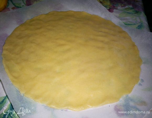 На бумаге для выпечки чертим круг диаметром 23 см. Раскатываем один шарик очень тонким слоем в пределах этого круга. Слой теста будет очень тонким, почти прозрачным. Я тесто просто распределяю руками, присыпая его мукой.