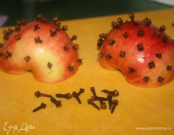 Яблоко разрезать пополам и аккуратно проткнуть его бутонами гвоздики, разрезать апельсин на тонкие кружочки.