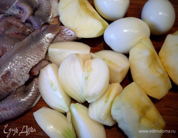 Хлеб отжимаем. Яблоко освобождаем от сердцевины и режем на крупные кусочки, т.е. четвертинки разрезаем и режем пополам. Сельдь режем на куски. Лук чистим и режем каждый примерно на четыре части. 