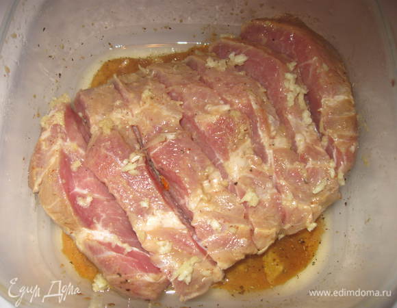 Вынуть мясо из холодильника. Сделать на нем глубокие поперечные надрезы. Чеснок пропустить через пресс и натереть им внутреннюю часть надрезов. 