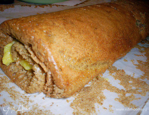 Выпекаем наш бисквит на противне размером 30*40 см, застеленном пергаментом. Тесто получается довольно жидкое и прекрасно распределяется по противню. Выпекаем в разогретой до 190-200 градусов духовке около 15 минут (у меня 20 минут). Даем бисквиту остыть до теплого состояния на противне, а затем скручиваем в рулет при помощи пергамента, на котором он выпекался.
Полностью остывший рулет осторожно разворачиваем и смазываем апельсиновым курдом, вновь скручиваем, заматываем в пергамент, завязываем края бумаги как конфетную обертку и отправляем его в морозилку, желательно на ночь.
