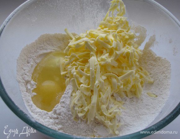 Натереть сливочное масло на крупной терке и смешать с мукой, яйцом, сахарной пудрой, ванилином и разрыхлителем.