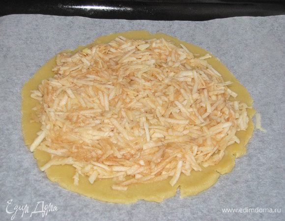 Выложить на тесто яблоки, натертые на крупной терке. Начинку выкладываем немного не доходя до края.