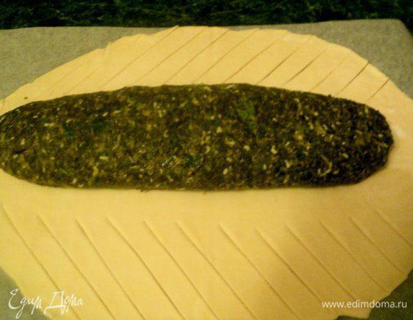 Тесто раскатать в виде овала, по центру положить лосось в шпинатной шубке. По бокам на тесте сделать косые надрезы шириной 1.0 см.