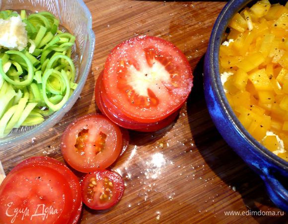 Тем временем мелко режем желтый перец, лук-порей нарезаем кольцами (белую и светлозеленую его часть), мелко крошим сыр Фета. Чеснок трем на мелкой терке. Помидоры режем тонкими колечками. Посыпаем их солью и перцем, ставим пирамидкой и сверху добавляем капельки две оливкового масла. Твердый сыр натираем на терке.