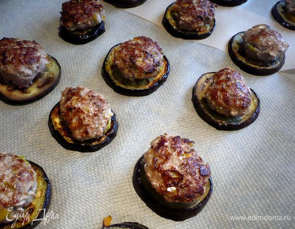 Духовку разогреваем до 180 градусов. Котлеты обжариваем с двух сторон в оливковом масле, по 3 - 4 минуты с каждой стороны на сильном огне. Половину колечек баклажана выкладываем на застеленный пекарской бумагой противень. Сверху кладем наши бургеры. 