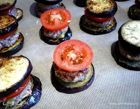 На каждый бургер выкладываем по ломтику помидора, сверху накрываем колечком баклажана. Густо посыпаем сверху твердым сыром. Ставим в духовку на 15 - 20 минут.