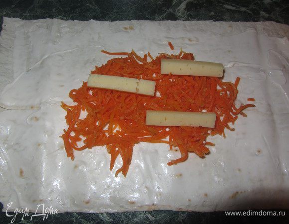 Сыр порезать длинными ломтиками и выкладывать по пару кусочков на морковку.
