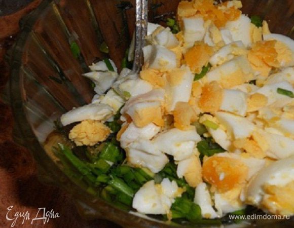 Добавить порезанные кубиками вареные яйца к зелени, посолить и поперчить, перемешать.