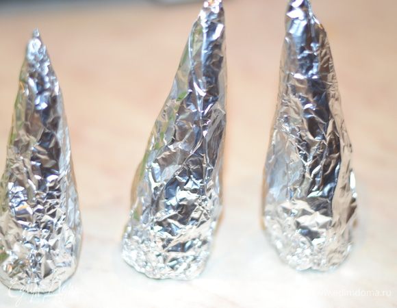 Смастерить из фольги треугольнички, сначала оторвать немного фольги, пожмякать, затем руками скатать треугольник, завернуть еще раз в фольгу, постучать по столу низом. чтоб он был ровным.