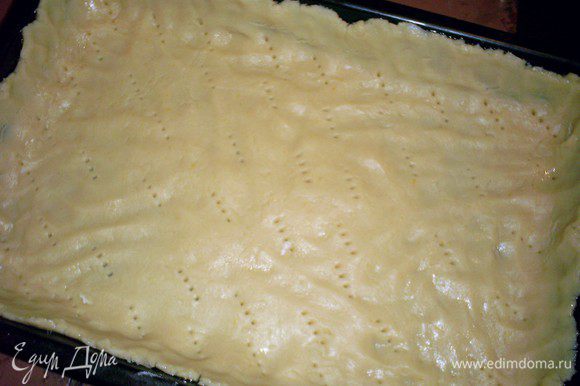 Делим тесто на две неравные части. Большую часть распределяем руками по форме 25х30 см, смазанной маслом или маргарином. Накалываем тесто вилкой.