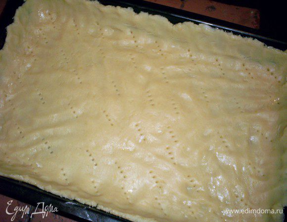 Делим тесто на две неравные  части. Большую часть распределяем руками по форме 25х30 см, смазанной маслом или маргарином. Накалываем тесто вилкой.