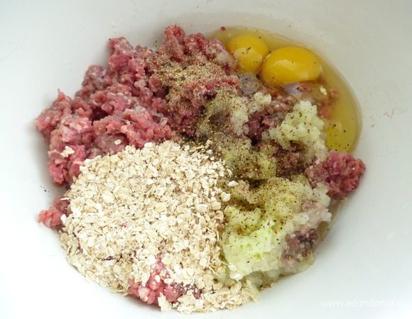 Мясо пропустить через мясорубку вместе с репчатым луком. Добавить яйцо, овсяные хлопья, молоко, измельченный чеснок, соль и молотый перец.