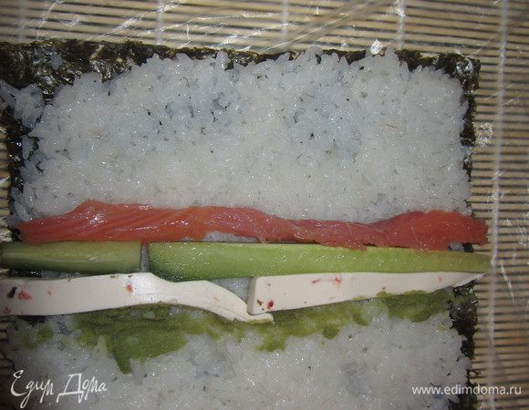 На середину выложите рыбу, огурец и сыр. Можно еще добавить васаби, но немного.