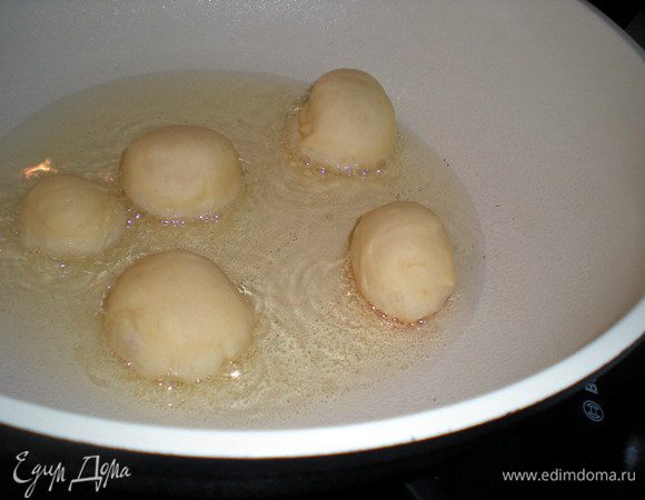 Налить масло в сковороду. Примерно через 15 минут масло достигнет нужной температуры. Лопаточкой подхватывать пончики по одному и осторожно опускать в масло. Не кладите сразу много шариков за один раз. Через 30-40 секунд пока пончики не начнут темнеть, затем перевернуть и жарить с другой стороны до равномерного цвета.