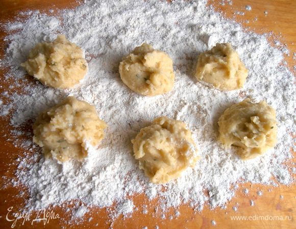 На доску густо сыплем слой муки и выкладываем при помощи двух ложек порции картофельной массы.