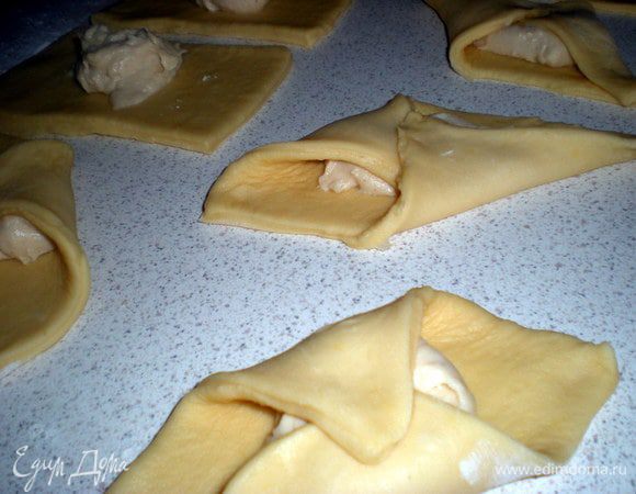 Выложить в центр каждого по столовой ложки бешамеля. Завернуть два противоположных конца к центру.