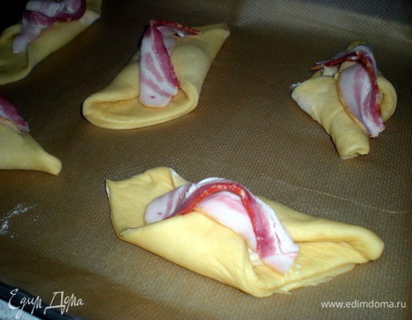 Сверху положить ломтик бекона. Переложить конвертики на противень,накрыть пергаментом,а сверху полотенцем.Оставить на 45 минут.Разболтать яйцо с солью.Духовку разогреть до 250 гр.