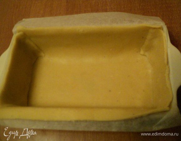 Затем тесто тонко раскатать между слоями пищевой пленки, вырезать пласты необходимых размеров и выложить бока и дно формы для выпечки (у меня размером 12х26 см). Форму предварительно застелить бумагой для выпечки и смазать маслом.