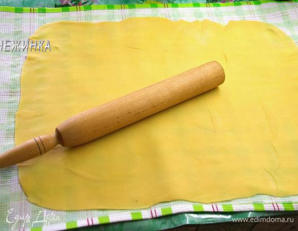 На рабочую поверхность стелим полотенце, присыпаем его мукой. Раскатываем на нём тесто по возможности тонко в виде прямоугольника (~ 38 х 49 см).