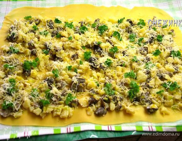 На тесто равномерно распределяем начинку, оставив верхний край немного свободным. Сверху распределяем листики петрушки и посыпаем оставшимся сыром.