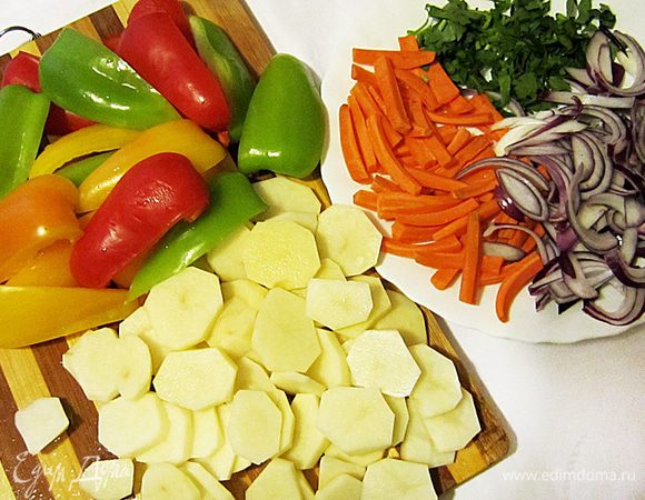 Подготовить овощи: картофель нарезать кружочками, морковь брусочками, каждый перец нарезать на 6 долек (удалив предварительно сердцевины), лук очистить и крупно нарезать. Петрушку порубить. 