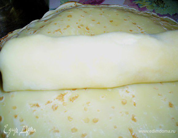 Сверните блин рулетиком, загибая внутрь края. Полученный рулетик разрежьте поперек на 2 равных части.