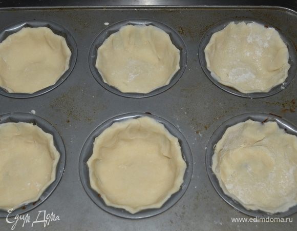 Выложим тесто в формы. Тесто слегка прижмем по краям формочек.