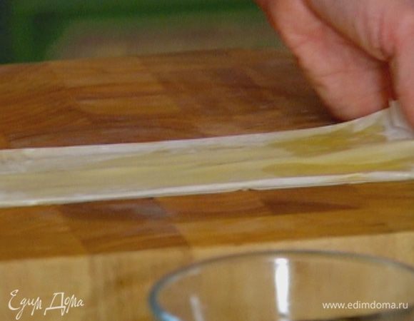 Лист теста фило свернуть пополам, промазать растопленным сливочным маслом, свернуть еще раз пополам и снова промазать маслом. Должна получиться длинная полоска из теста.