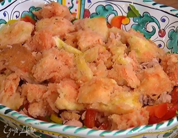 В блюдо с нарезанными овощами слоями выложить половину нарезанных помидоров, затем тунец и хлеб, вымоченный в соке помидоров.