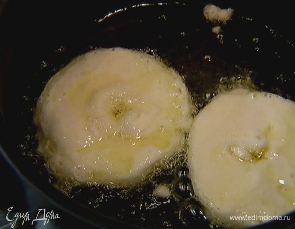 Опускать в кляр яблочные кольца и жарить их в кипящем масле до румяной корочки.