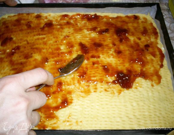 Приготовление песочного коржа:
Холодное масло (маргарин) растираем с сахаром, добавляем желтки и сметану. Постепенно добавляя муку, замешиваем мягкое тесто. Оно может слегка липнуть к рукам. Это нормально. Тесто делим на две части.
Заранее выстилаем пергаментом две одинаковых формы для выпечки. Распределяем по ним тонким слоем песочное тесто, накалываем вилкой и смазываем джемом.