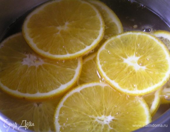 Приготовить декор-начинку. Вскипятить воду, добавить сахар и перемешать до растворения, добавить нарезанные тонкими ломтиками апельсины, варить 10-12 минут.
