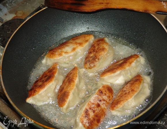 На горячую сковороду наливаем кунжутное масло, выкладываем гёдза вверх защипом. Держим так до появления корочки, уменьшаем огонь. Доливаем в сковороду воду до середины высоты пельменей. Прикрываем крышкой и готовим около 15 минут. Едим, окуная в соус.
