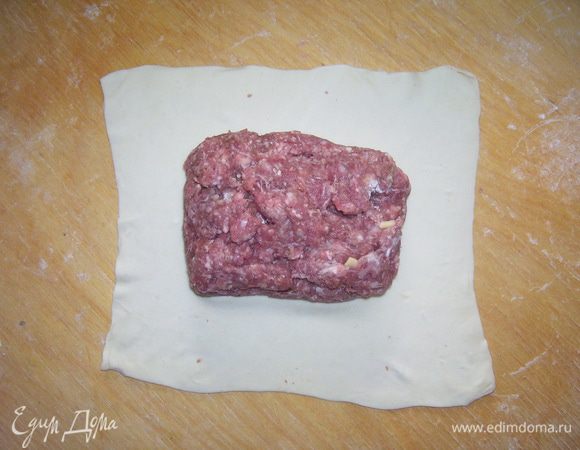 Раскатать тесто и нарезать на большие прямоугольники. На тесто выложить рулет и завернуть.