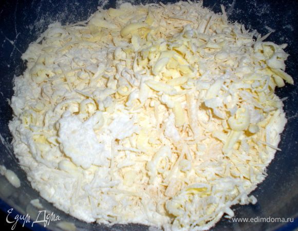 Сыр натереть на крупной терке. Масло замороженное так же натереть в муку, добавить яйцо и замесить тесто. Если получается суховатое, то можно добавить столовую ложку холодной воды.