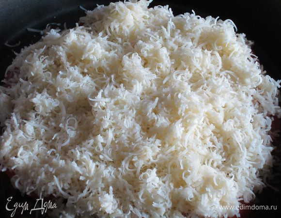 Духовку разогреть до 200°С. Сыр натереть на средней тёрке, помидоры нарезать тонкими кружочками. Пирог выложить на противень. Сверху выложить помидоры и посыпать тёртым сыром. Поставить в духовку на 10 мин.