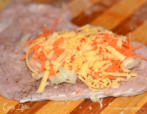 На отбитое, посоленное и приправленное мясо положить лук, морковь, сыр.