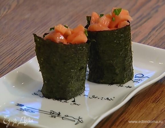 На край ворсистой стороны полоски нори выложить шарик из риса и свернуть рулетик. Поставить его «стаканчиком» и выложить сверху на рис кубики папайи.